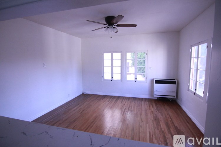 A room with a ceiling fan and a window with blinds.
