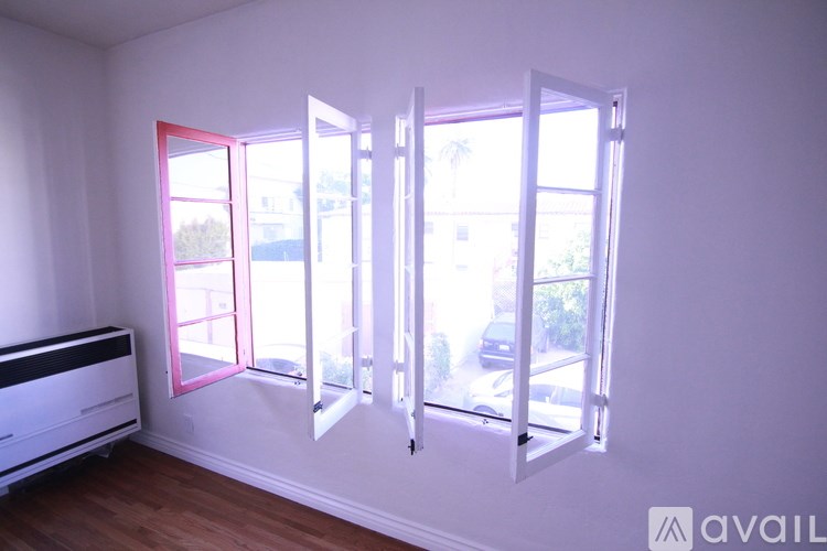 A room with a white wall and a window with pink trim.