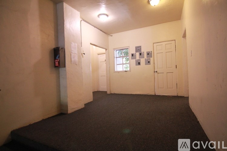 A room with a carpeted floor and a few electrical outlets on the wall.