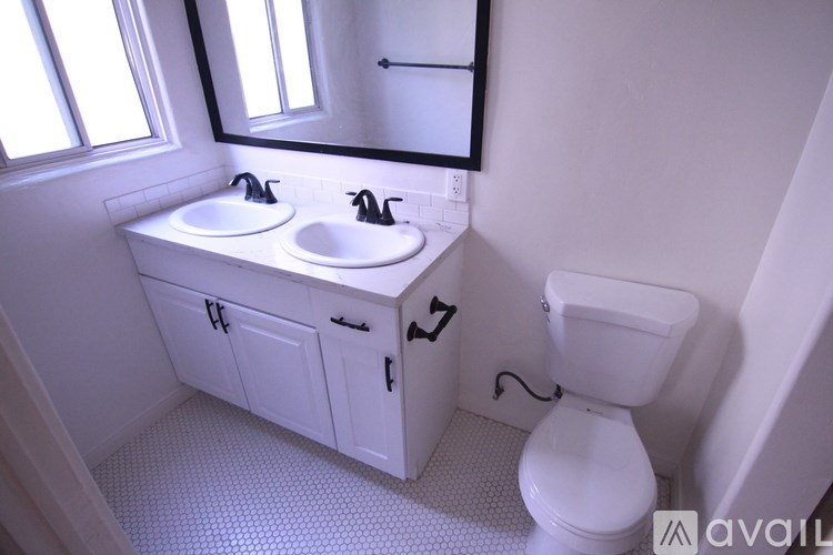 A white bathroom with a toilet, sink, and mirror.