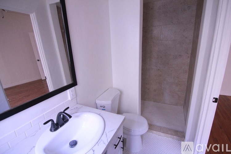 A bathroom with a toilet, sink, and mirror.