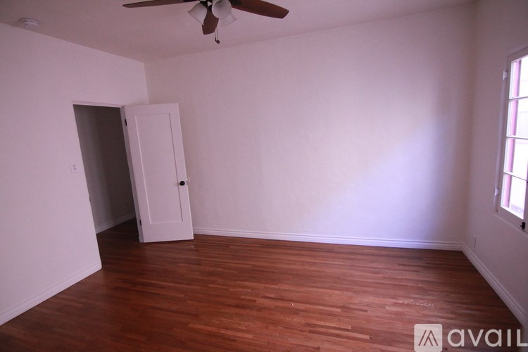A room with a ceiling fan and a door leading to another room.