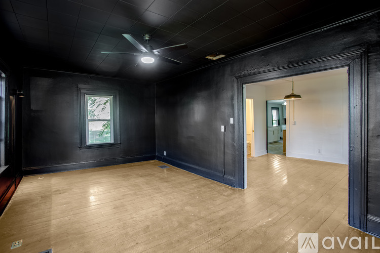 A room with wooden flooring and a window with a view of trees.