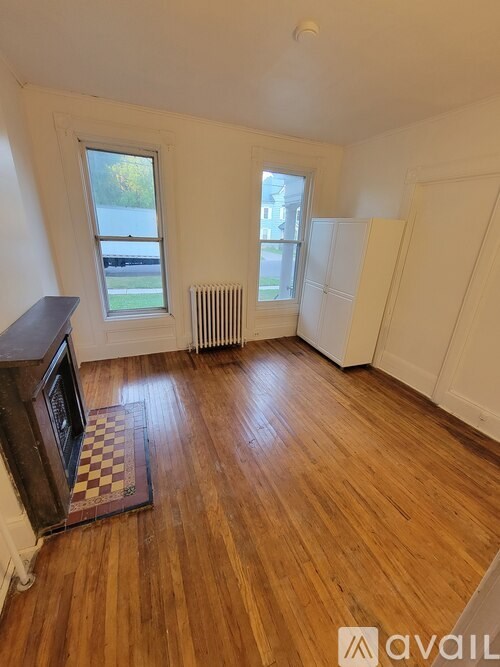 A room with wooden floors and two windows.