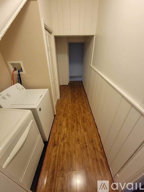 A long hallway with a washer and dryer on the left.