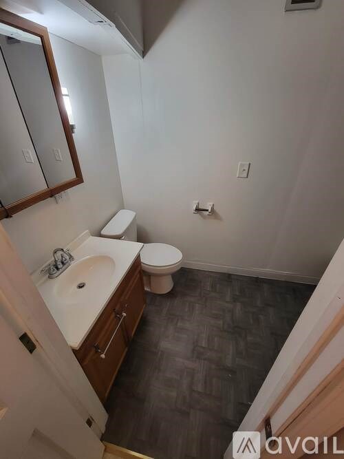 A bathroom with a toilet, sink, and mirror.