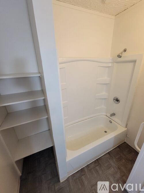 A white bathroom with a bathtub and a white shelving unit.