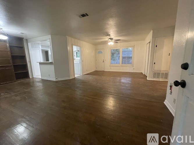 A spacious room with wooden flooring and white walls.