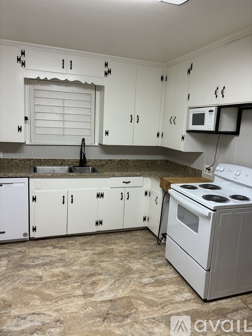 A kitchen with white cabinets and a white stove.