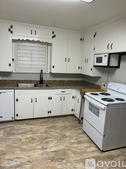 A kitchen with white cabinets and a white stove.