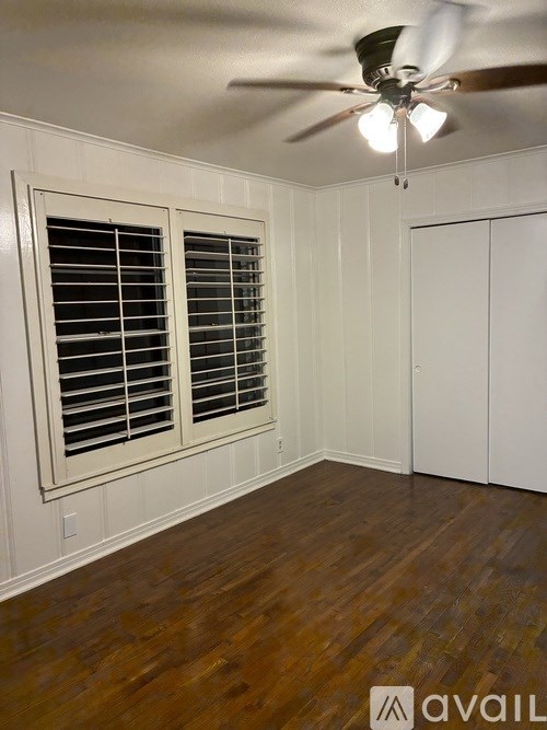 A room with a ceiling fan and a window with blinds.