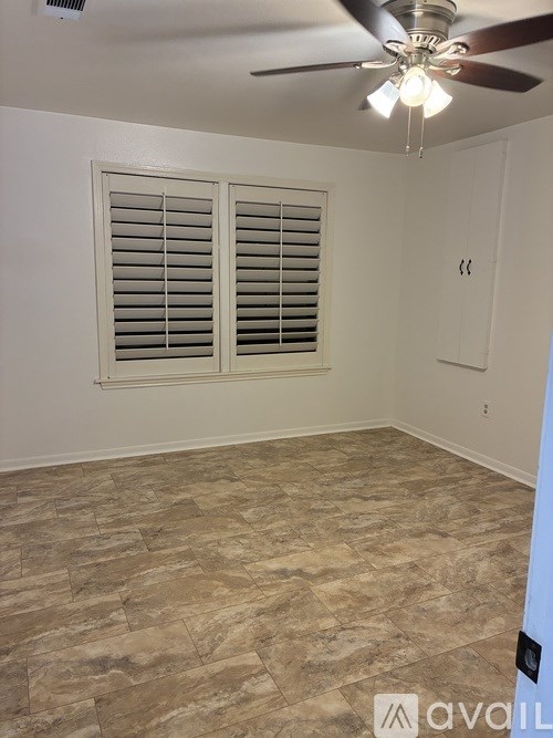 A room with a ceiling fan and a window with blinds.