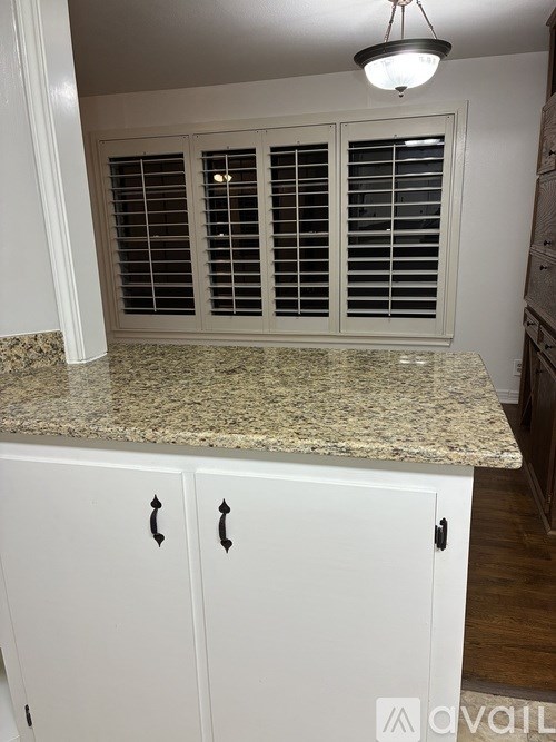A kitchen with a granite countertop and white cabinets.