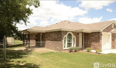A house with a brown roof and a white fence is for sale.