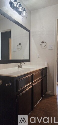 A bathroom with a white sink and brown cabinets.