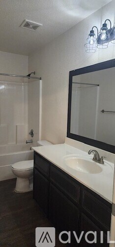 A bathroom with a toilet, sink, and mirror.