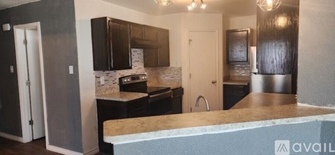 A kitchen with a granite countertop and a stainless steel refrigerator.