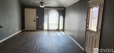 A room with a ceiling fan and sliding glass doors.