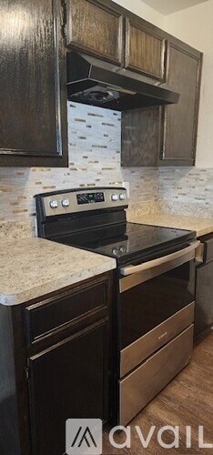 A kitchen with a black oven and wooden cabinets.