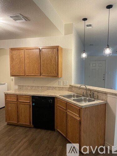 A kitchen with wooden cabinets and a black dishwasher.
