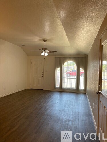 A room with a ceiling fan and sliding glass doors.