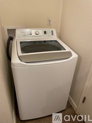 A white washing machine with a dryer on top is in a small room.