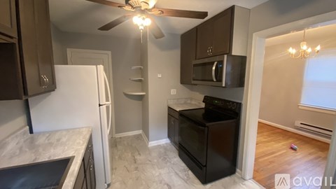 A kitchen with a white fridge, black oven, and microwave.