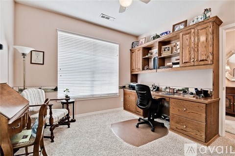 A room with a desk, chairs, and a bookshelf.