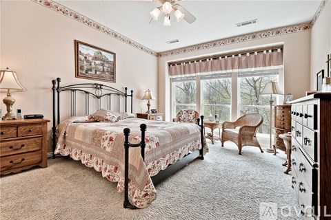 A bedroom with a large bed, a chair, and a painting on the wall.