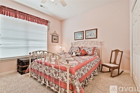 A bedroom with a bed, chair, and two pictures on the wall.