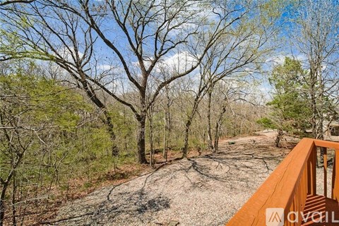 A wooded area with a dirt path and a wooden deck.
