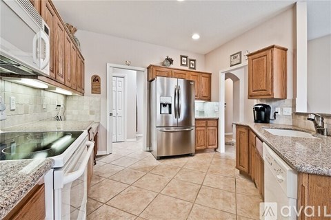 A kitchen with a refrigerator, sink, and cabinets.
