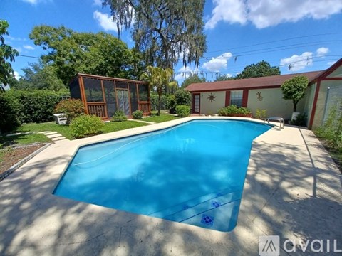 A swimming pool in a backyard with a house and trees in the background.