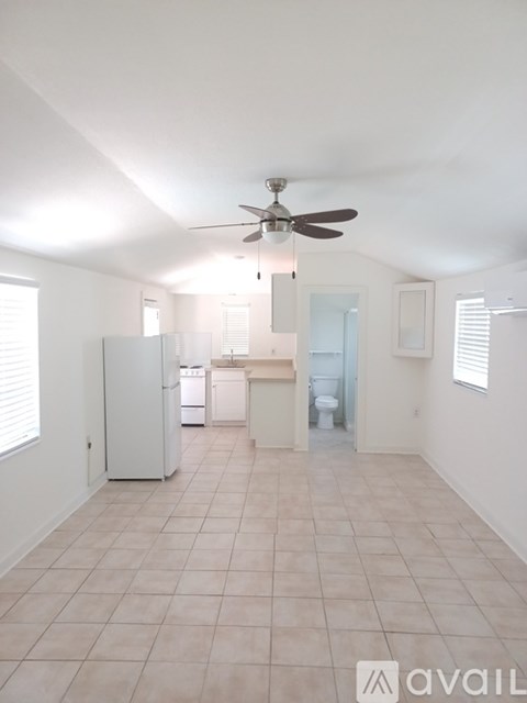 A spacious kitchen and living room with a fan and tiled flooring.