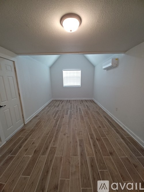 A room with wooden flooring and a window.
