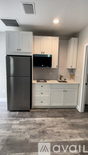 A kitchen with a black fridge and white cabinets.