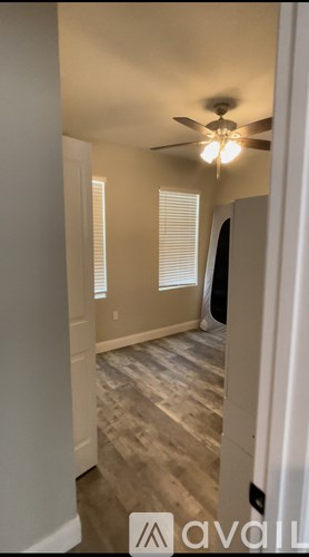 A room with a ceiling fan and a window with blinds.