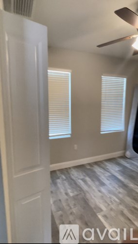 A room with a white door and a fan on the ceiling.