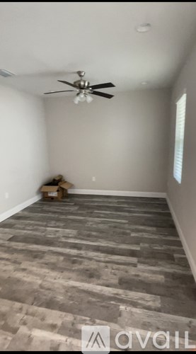 A room with a ceiling fan and wooden flooring.