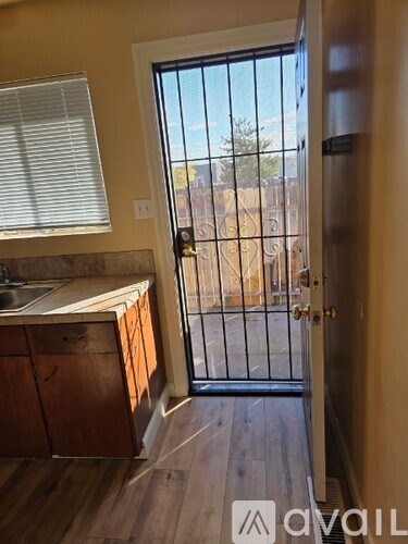 A kitchen with wooden cabinets and a sink is visible through a glass door.