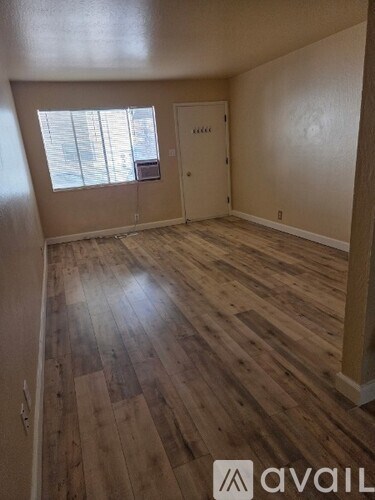 A room with wooden flooring and a window with blinds.