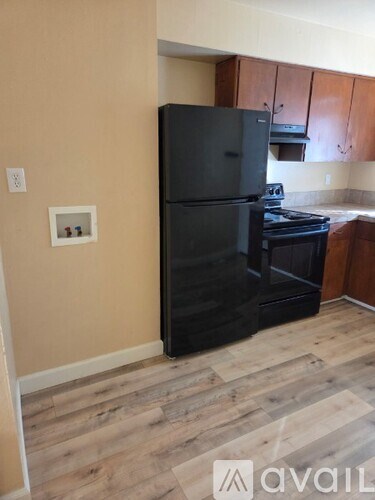 A black fridge in a kitchen with wooden flooring.