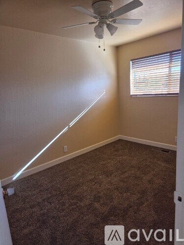 A room with a carpeted floor and a ceiling fan.