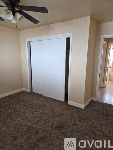A room with a carpeted floor and a ceiling fan.