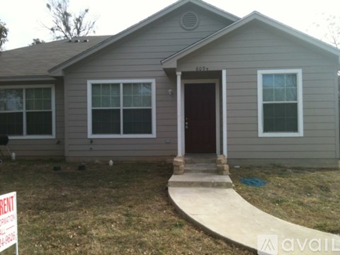A house with a brown door and a sign that says "RENT".