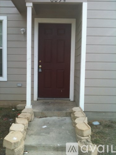 A brown door is at the end of a concrete walkway.