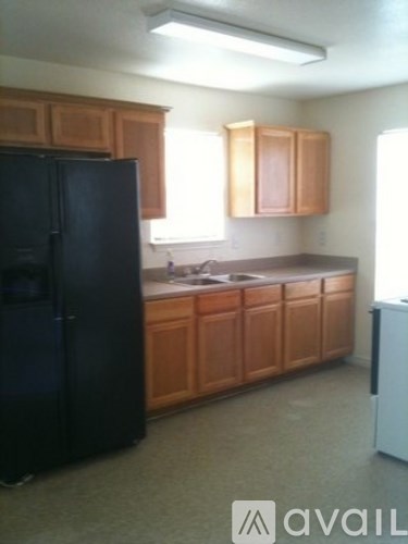 A kitchen with wooden cabinets and a black refrigerator.