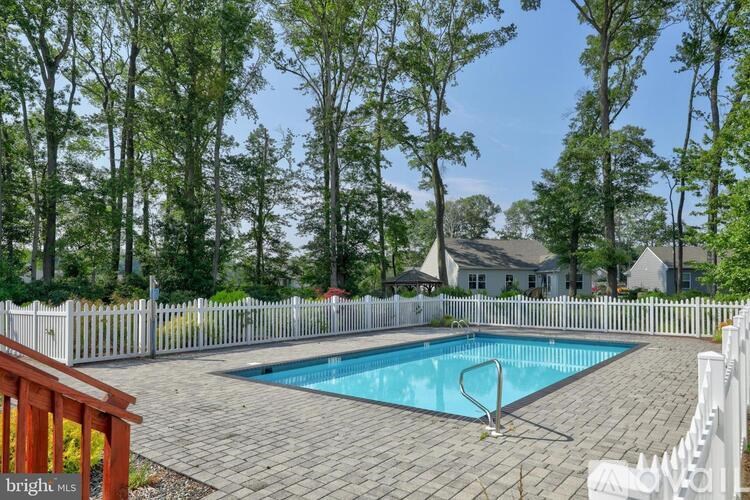 A pool surrounded by a white picket fence and trees.