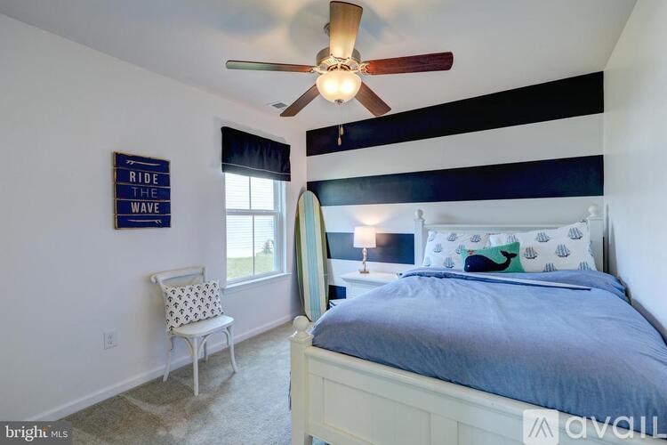 A bedroom with a bed, a chair, and a ceiling fan.