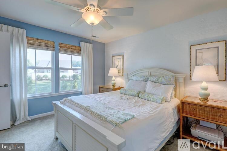 A bedroom with a large bed and a window with curtains.